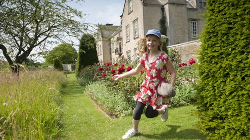 Girl running in the gardens in front of Nunnington Hall